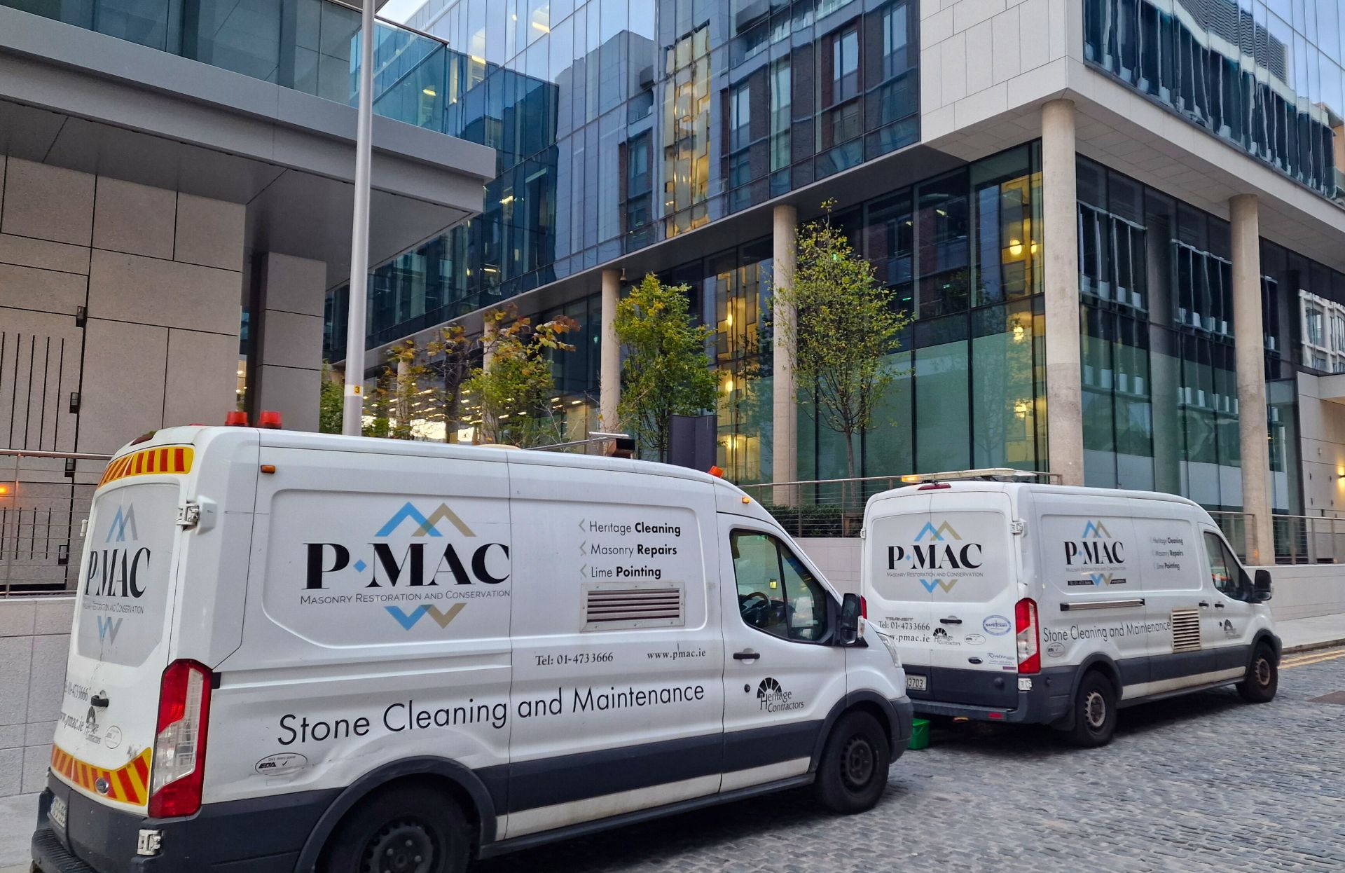 Two Pmac vans outside office building